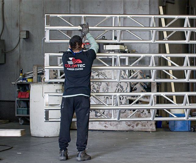 Colortec team member hanging a prepped truss on the facility guiding rail