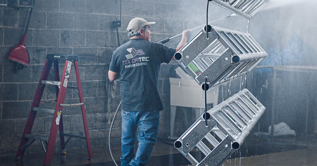 Colortec team member pressure washing hanging trusses before coating